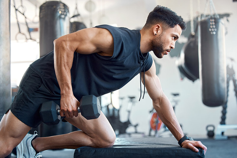 A bad day can be made better by going to the gym. Shot of a sporty young man exercising with a dumbbell in a gym.