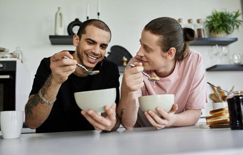 A young gay couple enjoys a leisurely breakfast together in thei